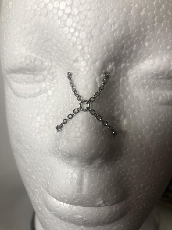 a white mannequin head with chains attached to it's face and eyes