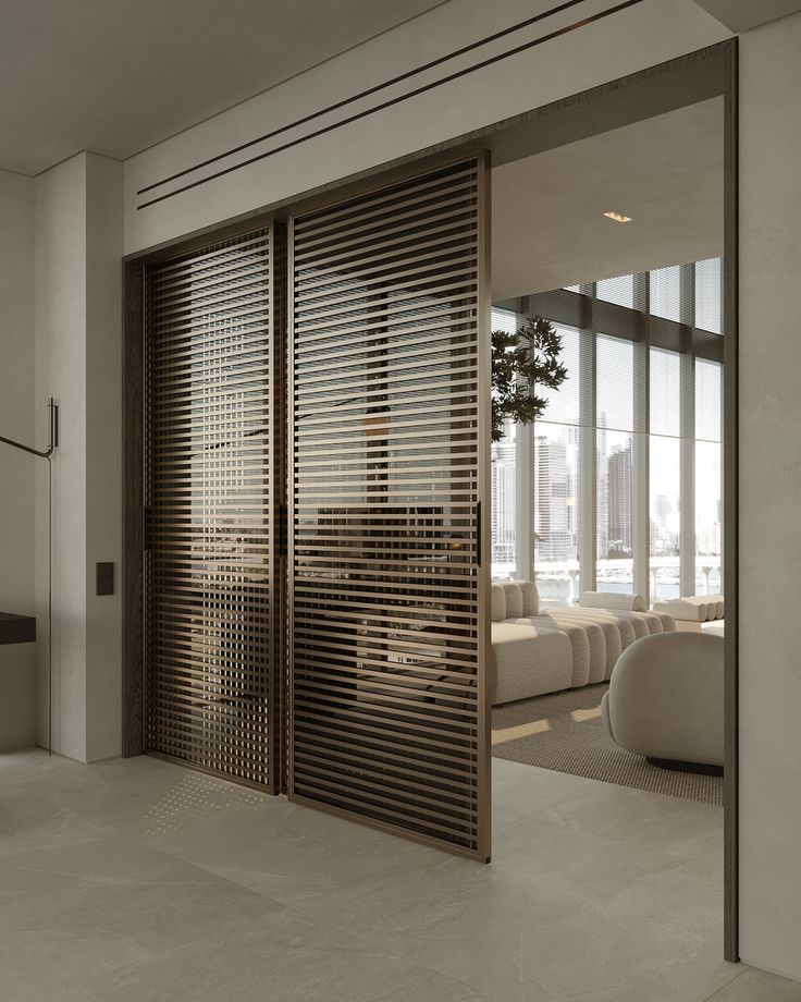 an open door leading to a living room with white couches and large glass windows