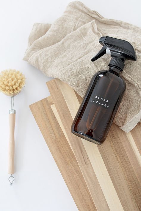 a bottle of soap next to a brush on top of a wooden cutting board with a cloth