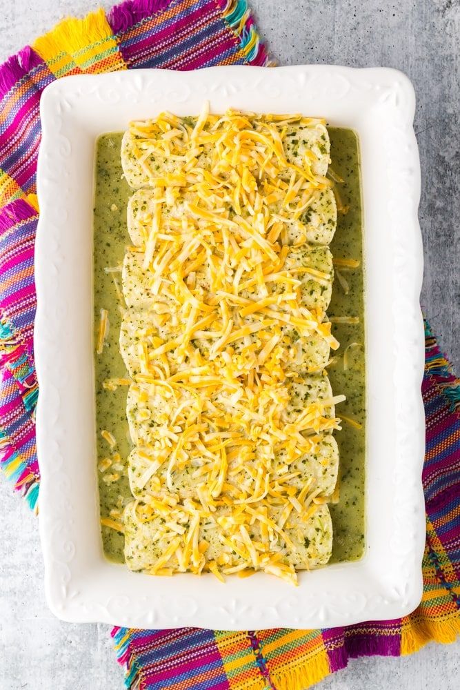 a square casserole dish filled with green sauce and cheese