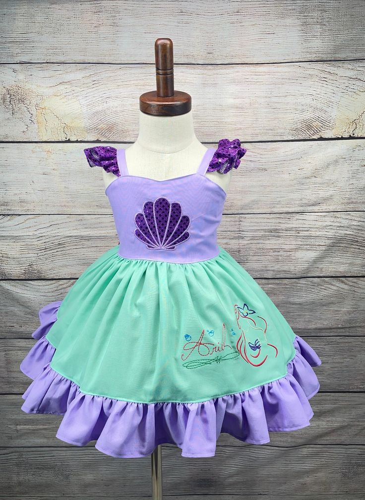 Haz realidad los sueños de tu pequeña con este encantador vestido inspirado en sirenas, inspirado en Ariel de "La Sirenita". Este vestido es la opción perfecta para cumpleaños y hará que tu niña se sienta como una verdadera princesa en su día especial. Con delicados volantes en los hombros y en el bajo de la falda, este vestido derrocha elegancia y encanto. Los detalles con volantes añaden un toque de fantasía, realzando el atractivo mágico del vestido. Tenga en cuenta que el tutú que se muestra en la foto no está incluido con el vestido. Se ha añadido debajo para una mejor presentación. Estamos orgullosos de la artesanía de nuestras prendas, y cada vestido está hecho con amor y atención al detalle. Debido a esta dedicación, el tiempo de producción de este vestido es de 3 a 5 días. Sin emb Princess Style Fitted Twirl Dress For Dress-up, Purple Mermaid Hem Summer Dress, Fitted Fairy Dress With Ruffles For Pageant, Fitted Ruffles Fairy Dress For Pageant, Purple Mermaid Hem Dress With Ruffles, Purple Ruffle Mermaid Hem Dress, Purple Ruffled Dress With Mermaid Hem, Purple Fitted Princess Dress, Fitted Purple Princess Dress