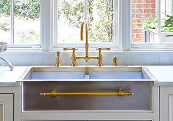 a kitchen sink with two faucets in front of it and windows behind it