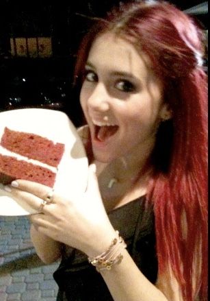 a woman with red hair holding up a piece of cake