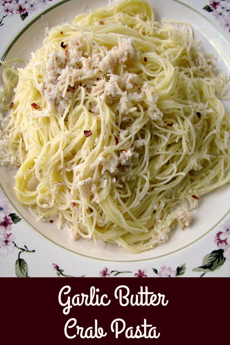 garlic butter pasta with parmesan cheese and herbs on a white plate, ready to be eaten