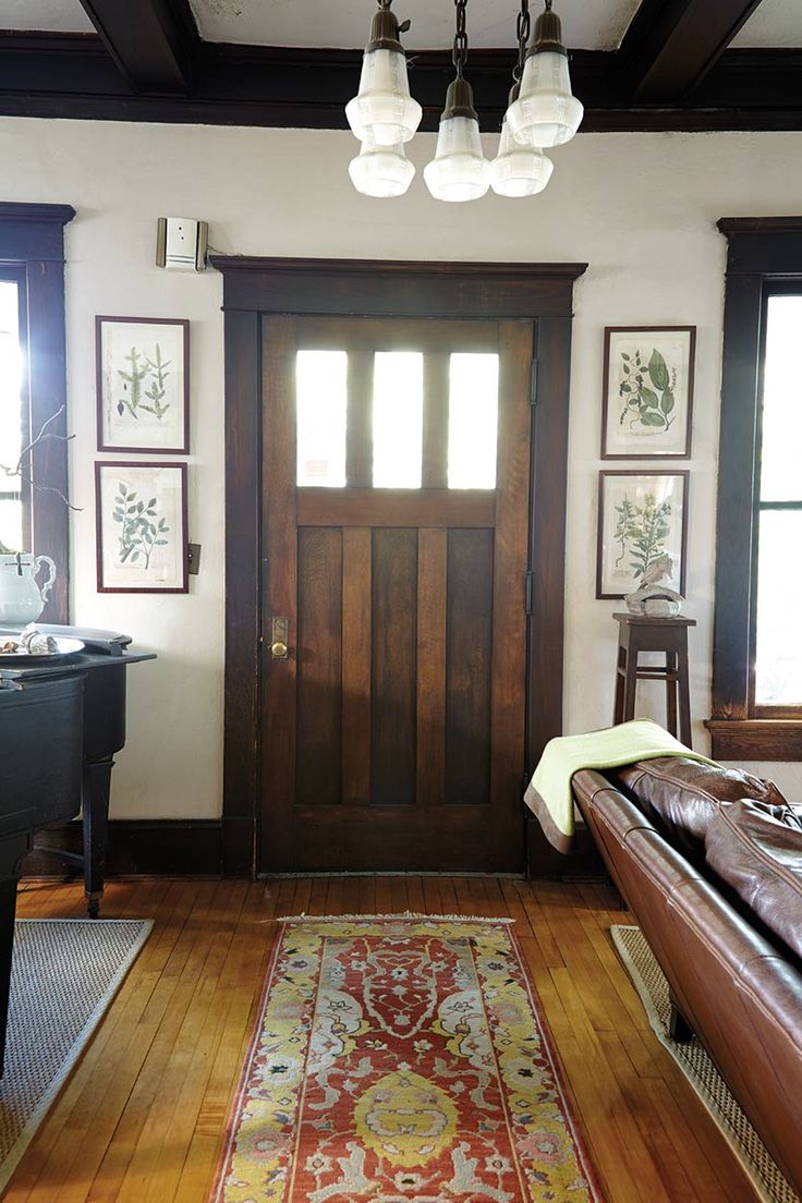 a living room filled with furniture and a piano in front of a wooden paneled door