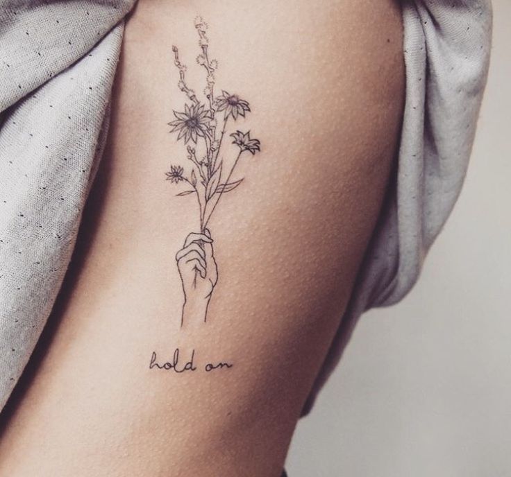 a woman's arm with flowers on it and the words hold on written in black ink