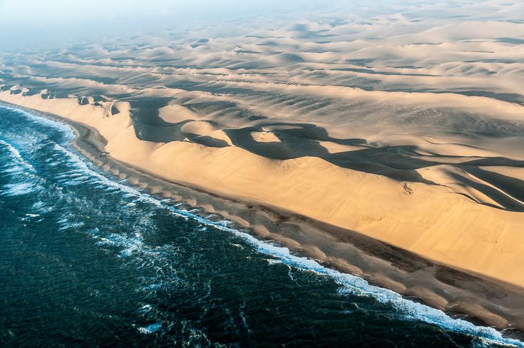 an aerial view of the sand dunes and ocean in the desert, taken from above