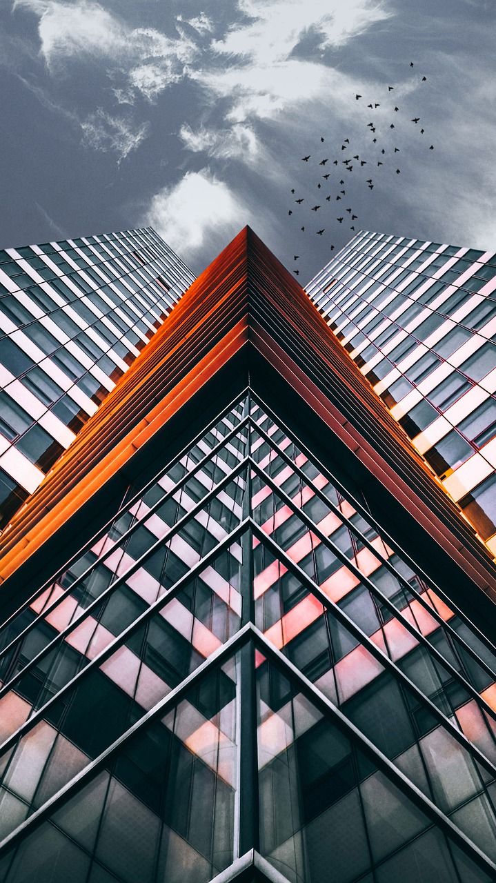 birds are flying in the sky above an office building