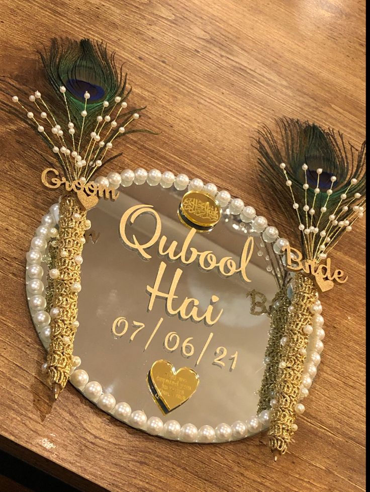 a cake decorated with peacock feathers on top of a wooden table next to a plaque