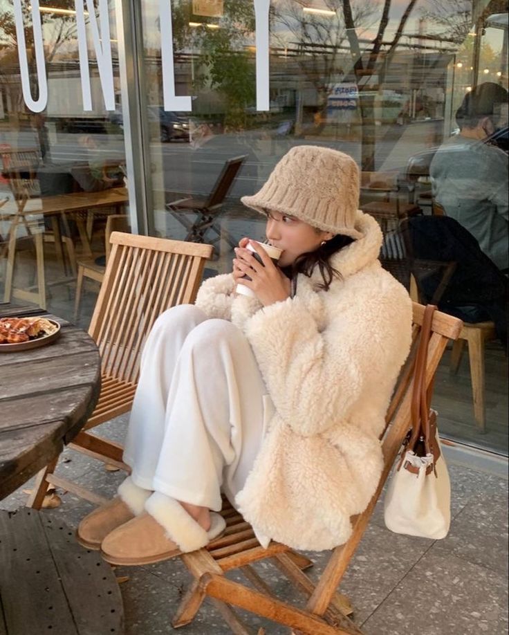 a woman sitting in a chair drinking from a cup