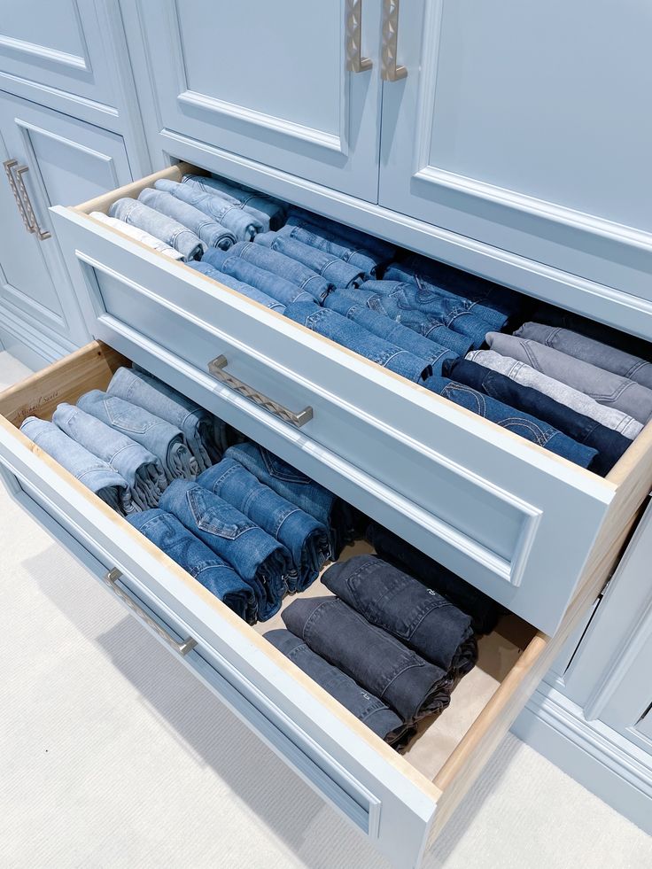 an open drawer with folded jeans in it