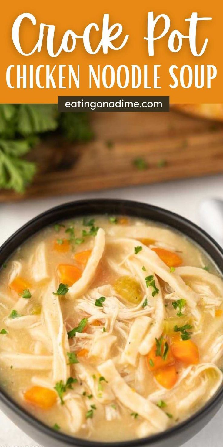 chicken noodle soup in a black bowl with carrots and parsley on the side