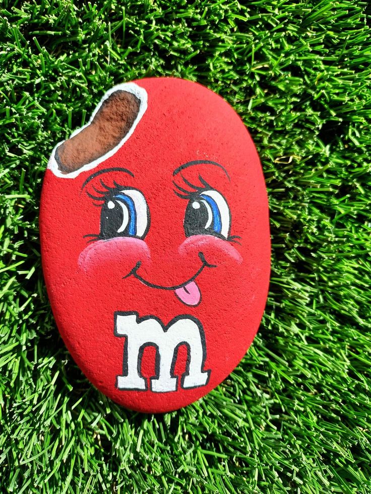 a red rock with m on it sitting in the grass