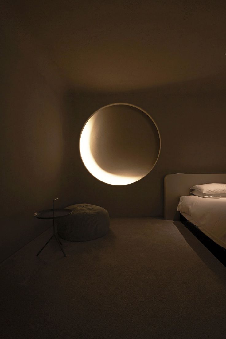 a bedroom with a bed and a round light fixture in the middle of the room