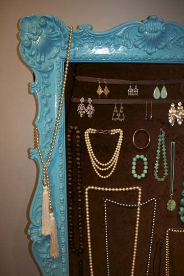 a blue framed mirror with jewelry hanging on it