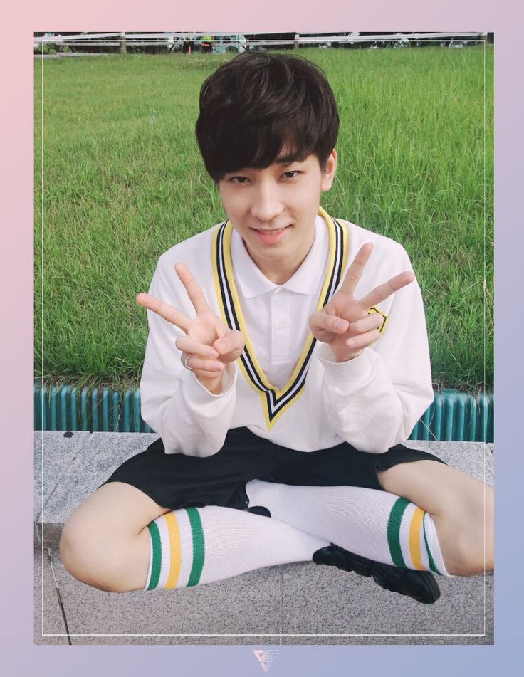 a young man sitting on the ground making peace signs