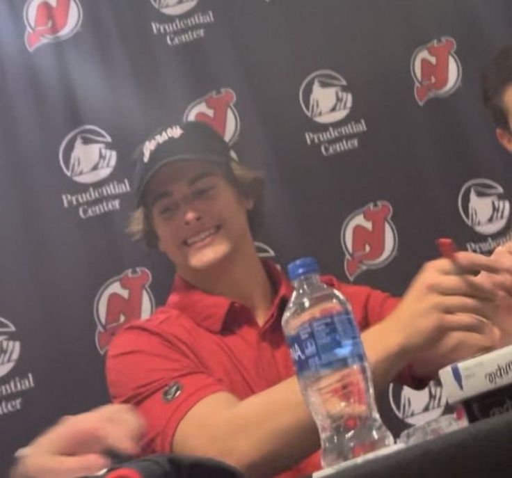 two men sitting at a table in front of a microphone with water bottles on it