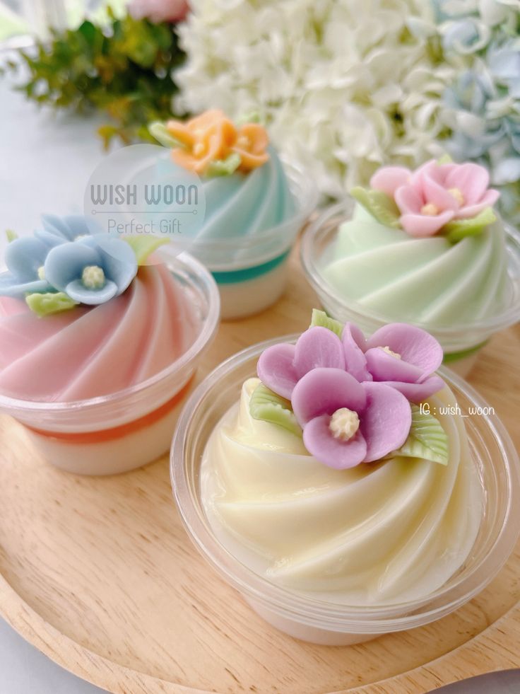 three small cupcakes with flowers in them on a wooden tray next to white and pink flowers