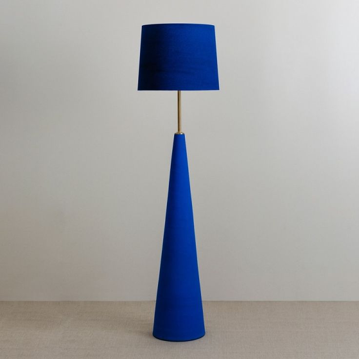 a blue lamp on a table next to a white wall