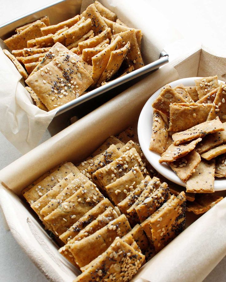 some crackers are sitting in a box next to a white plate with black sesame seeds on it