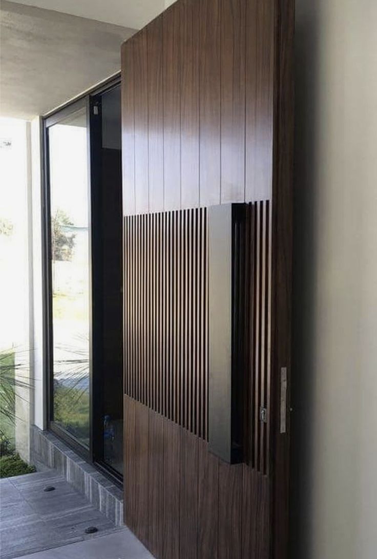 an entrance to a house with wooden slats on the side and glass doors in front