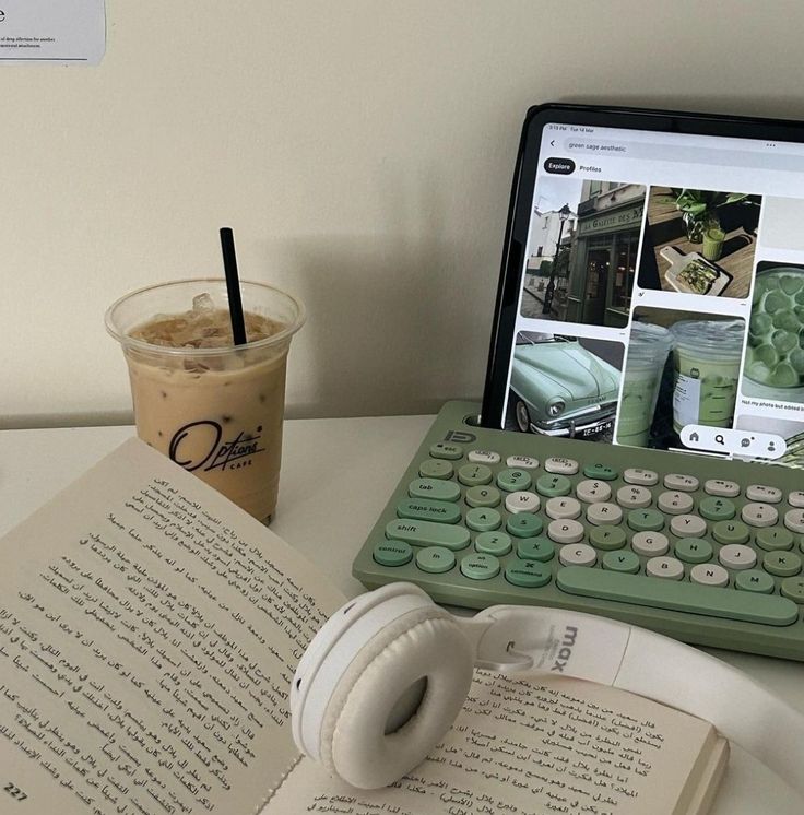 an open book sitting on top of a table next to a keyboard and cup of coffee