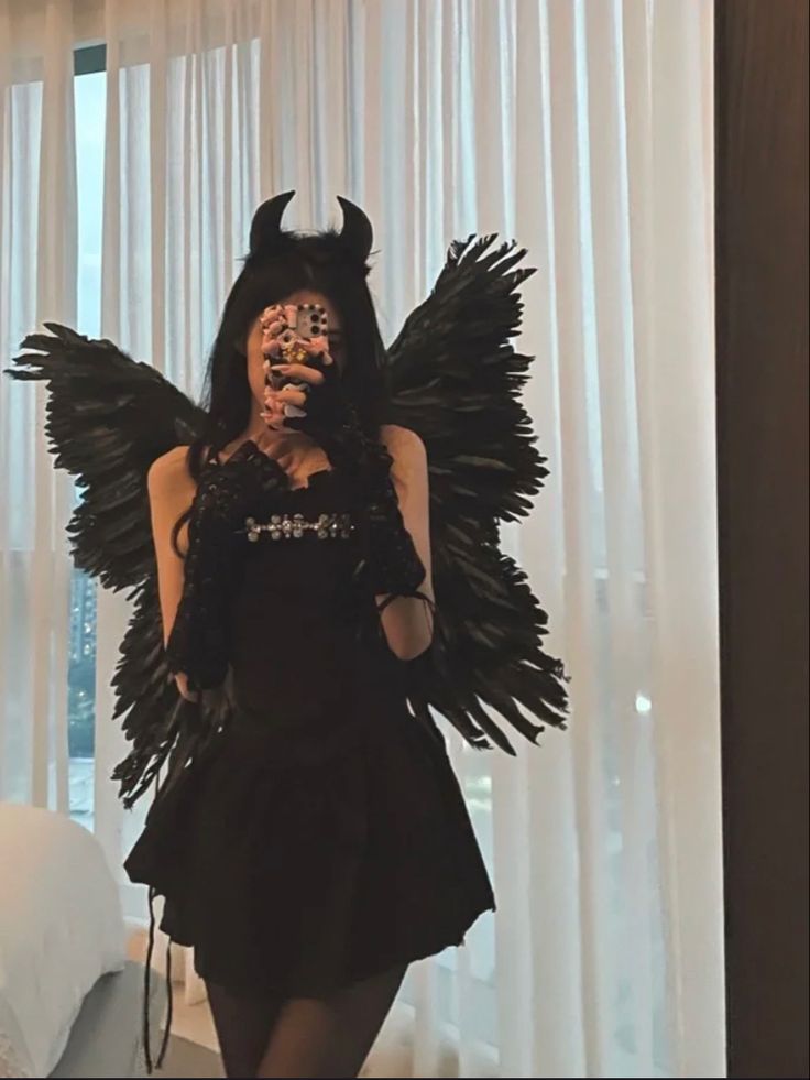 a woman dressed in black with wings and makeup