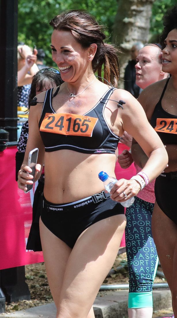 two women in swimsuits are running on the street and one is holding a water bottle