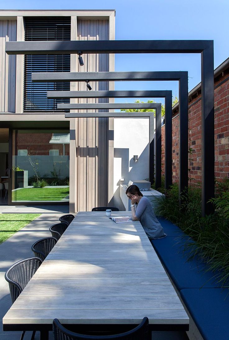 a person sitting at a long table with a laptop on it in front of a building