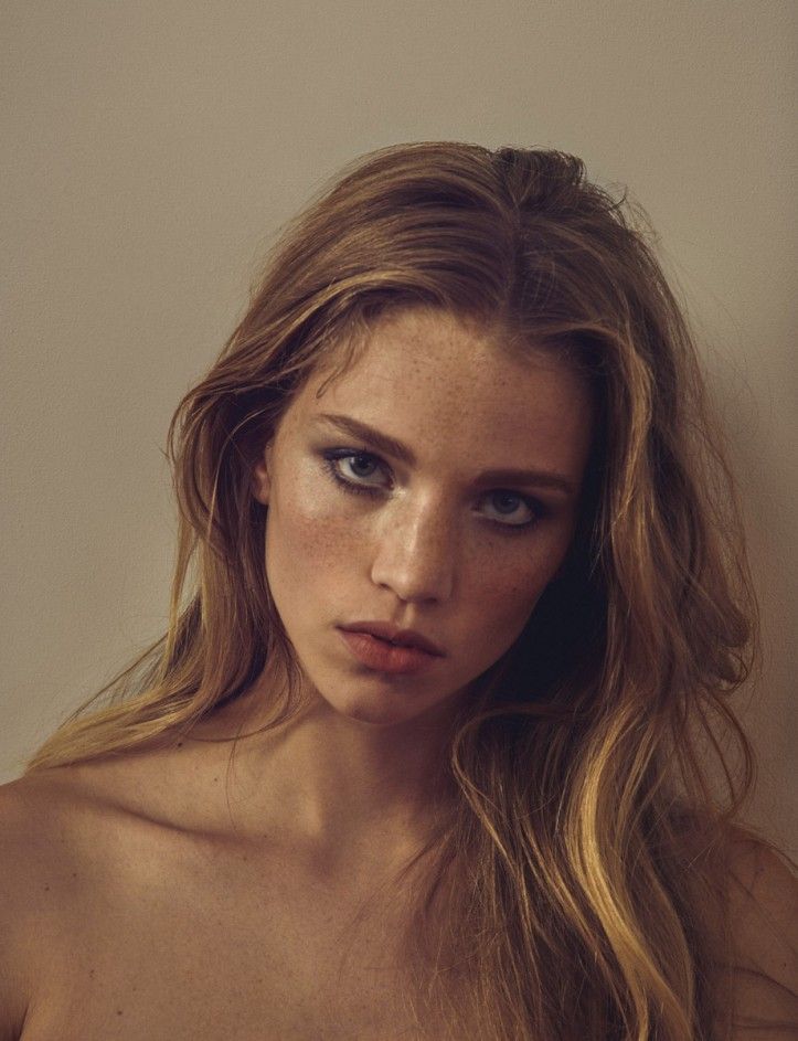 a young woman with freckled hair and blue eyes is posing for the camera