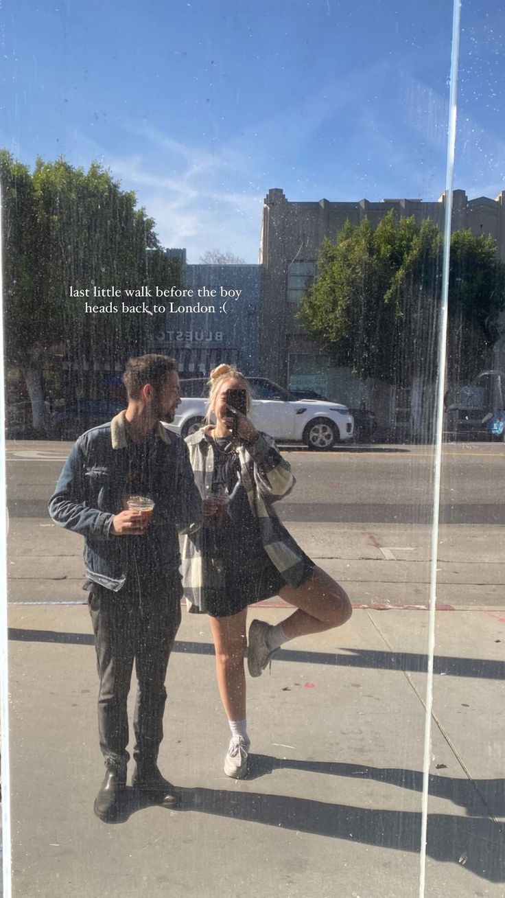 a man and woman standing next to each other in front of a window with a quote on it