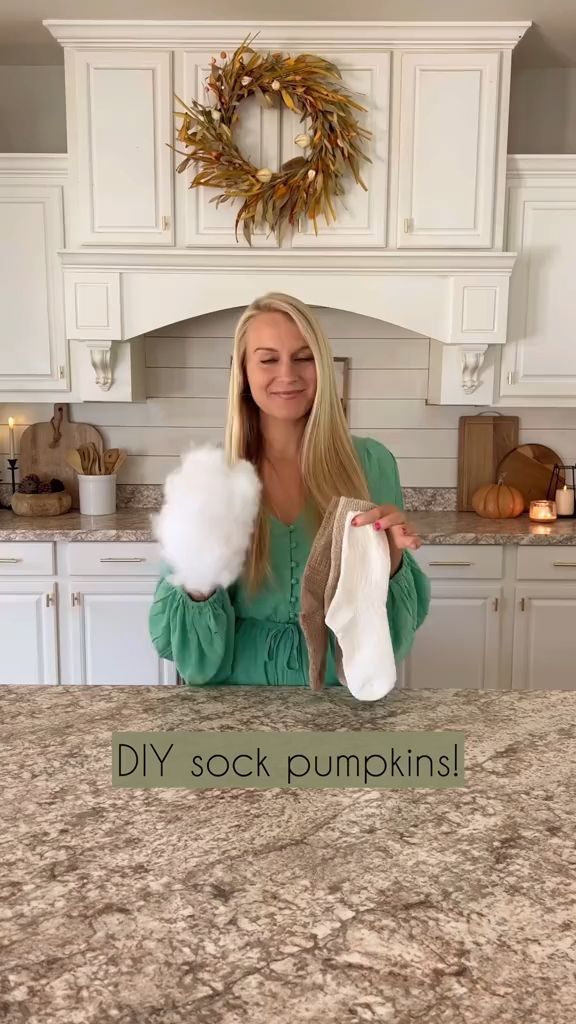 a woman holding two cotton balls in her hands with the words diy sock pumpkins