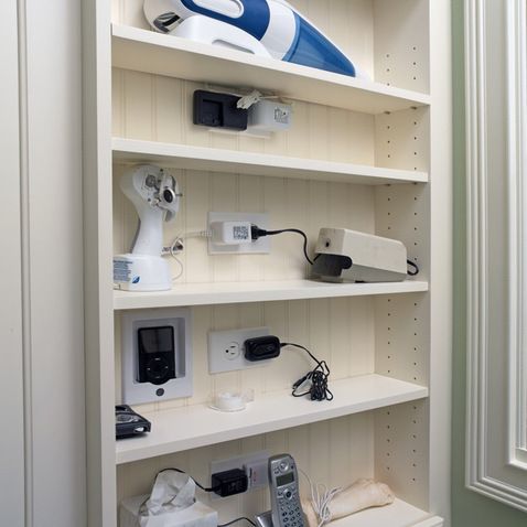 a white shelf filled with electronic devices and other household items on top of each shelf