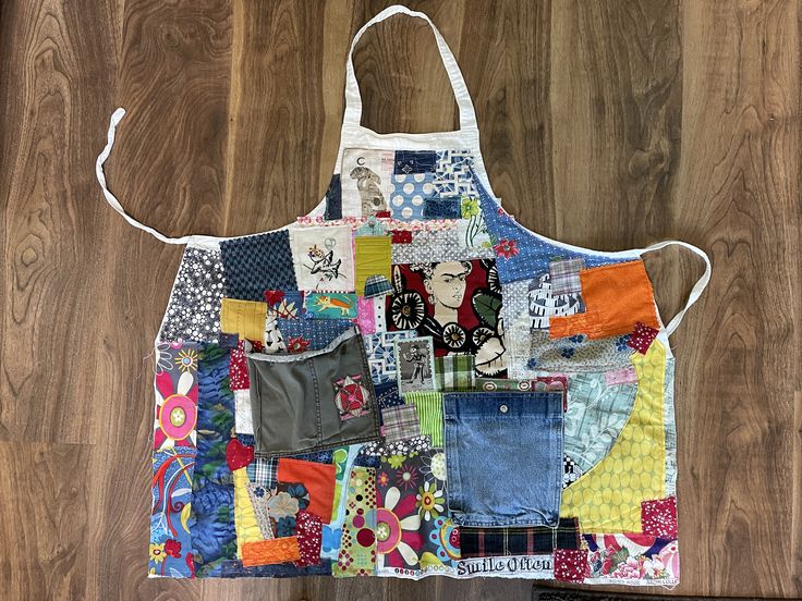 an apron made out of patchwork material on top of a wooden floor next to a bag