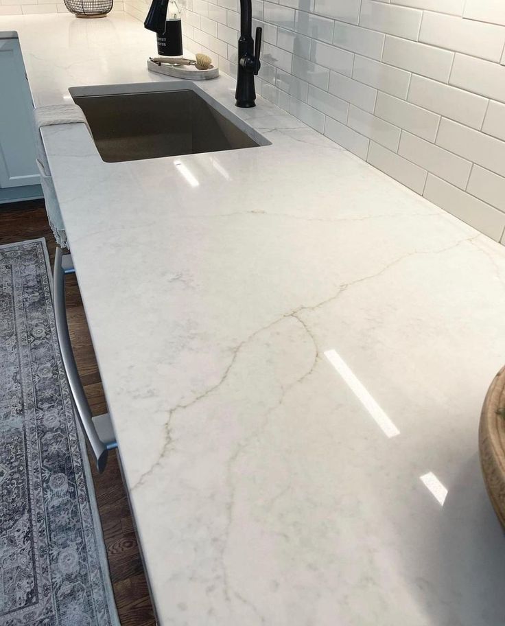 a white kitchen counter top next to a sink