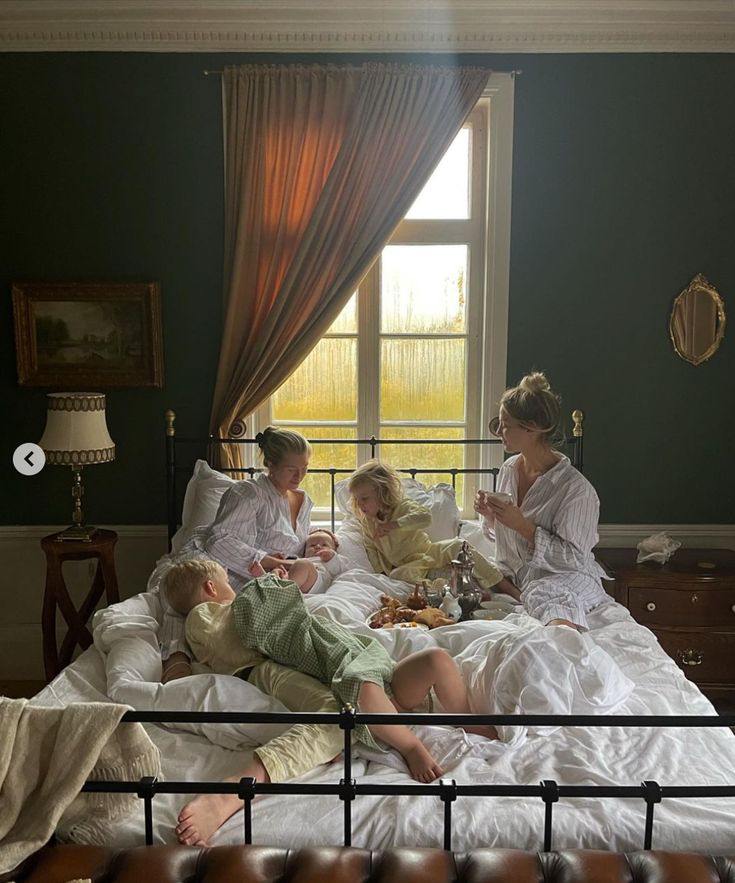 three women and two children sitting on a bed