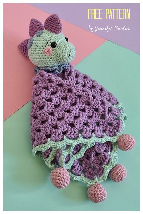 a crocheted stuffed animal sitting on top of a green and purple blanket with pink balls