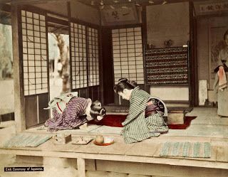 two geisha women in kimonos sitting at a table