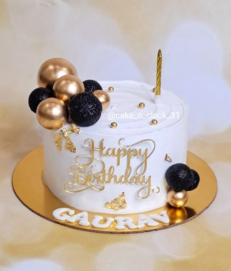 a birthday cake with gold and black decorations on it's side, sitting on a plate