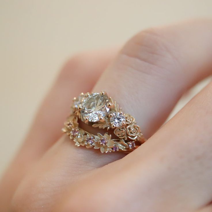 This is the biggest, most dramatic engagement ring I've ever designed. Inspired by gold roses in the Animal Crossing series, this ring features a huge 1 carat round brilliant cut diamond. On either side are accent diamonds surrounded by golden leaves and golden roses in clusters of three, just as they appear in the games.✶ solid 14 karat recycled yellow, white, or rose gold✶ band measures 1.4mm wide x 1.4mm thick✶ center stone: 1 carat, VS2 clarity, J color, very good cut, round brilliant cut di Dramatic Engagement Ring, Gold Victorian Engagement Ring, Engagement Ring Cottage Core, Cameo Engagement Ring, Creative Engagement Rings Gold, Rococo Engagement Ring, Insect Engagement Ring, Vintage Engagement Ring Sets, Vintage Royal Engagement Rings