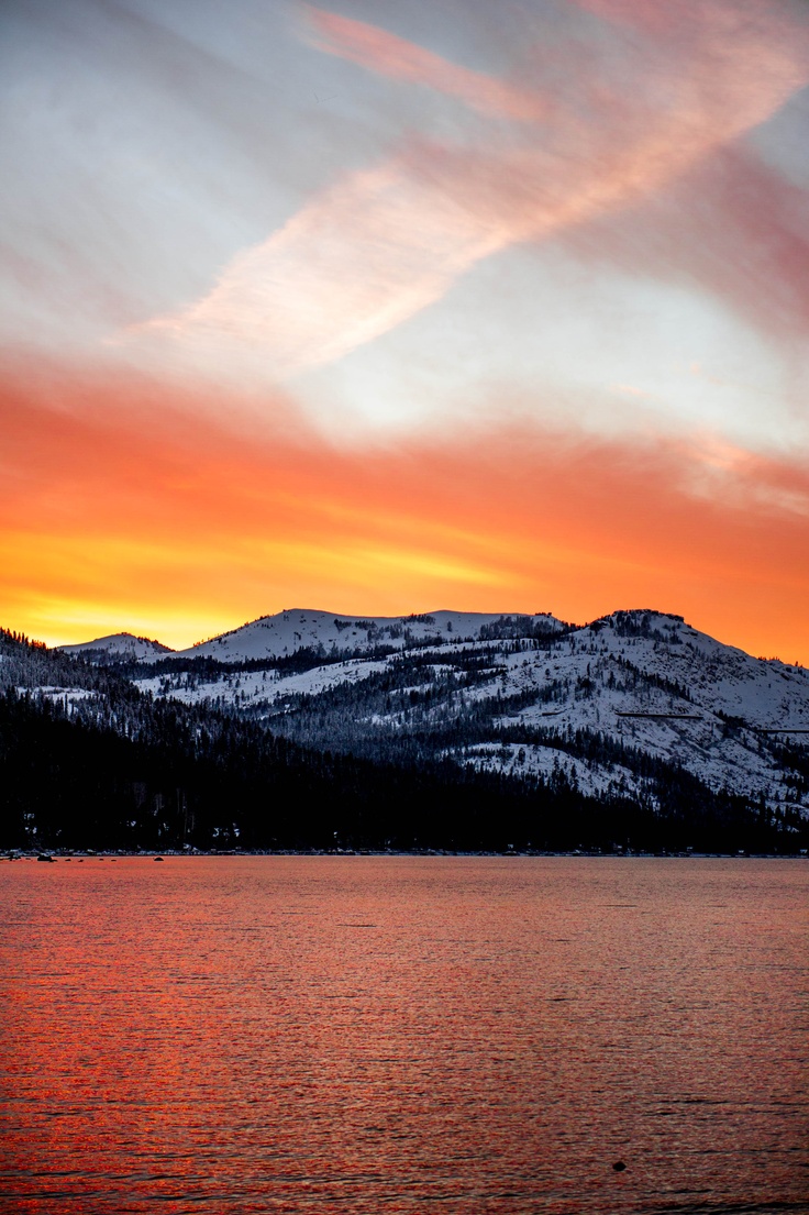 the sun is setting over mountains and water