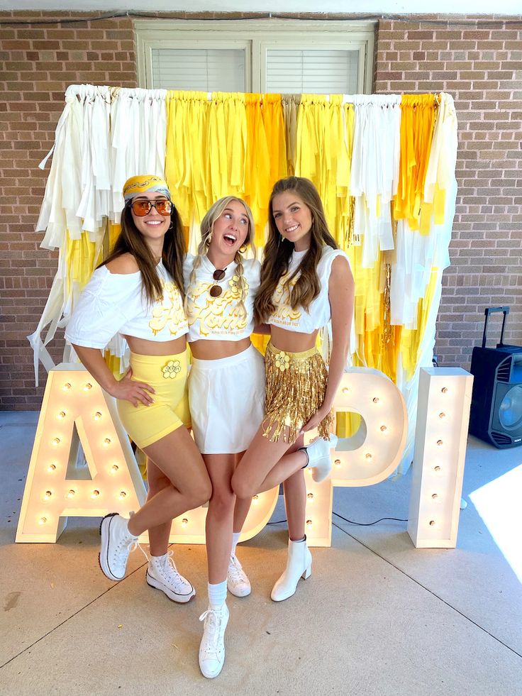 three young women posing in front of a sign