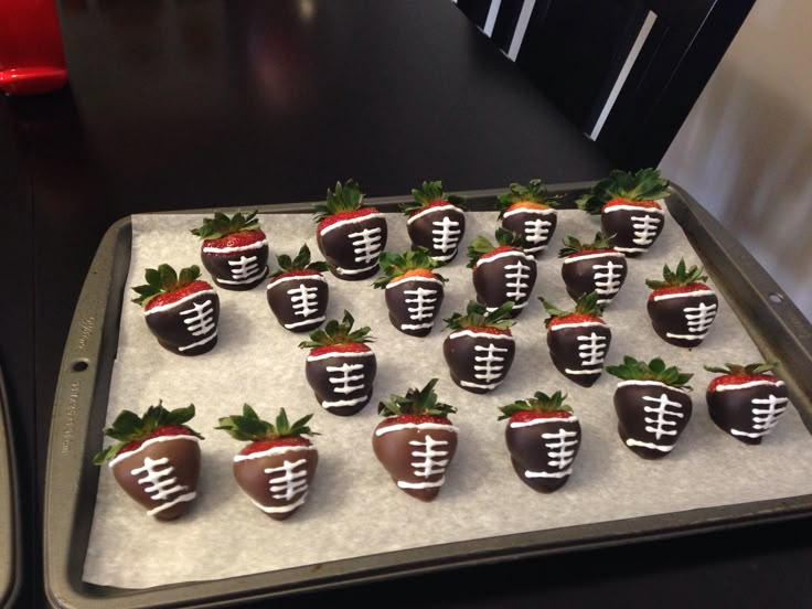 chocolate covered strawberries are arranged in the shape of footballs on a baking sheet