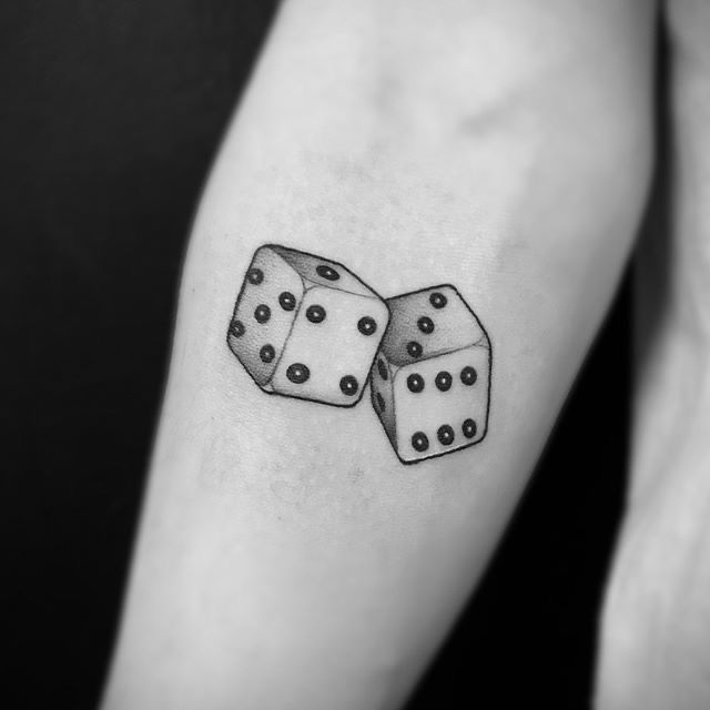 two dices on the arm with one being bigger than the other, both in black and white