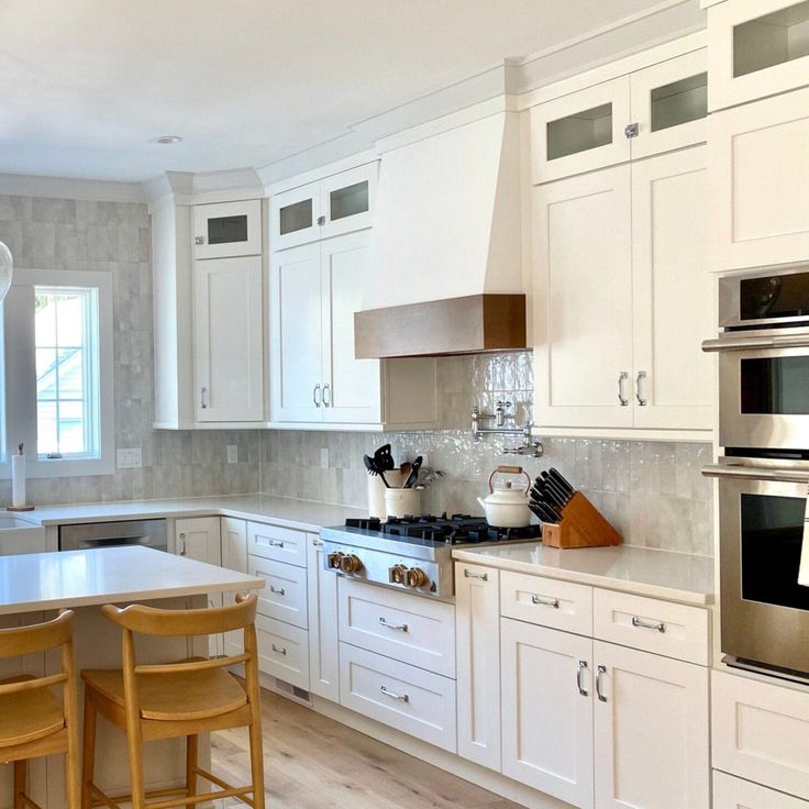 a kitchen with white cabinets and wooden chairs