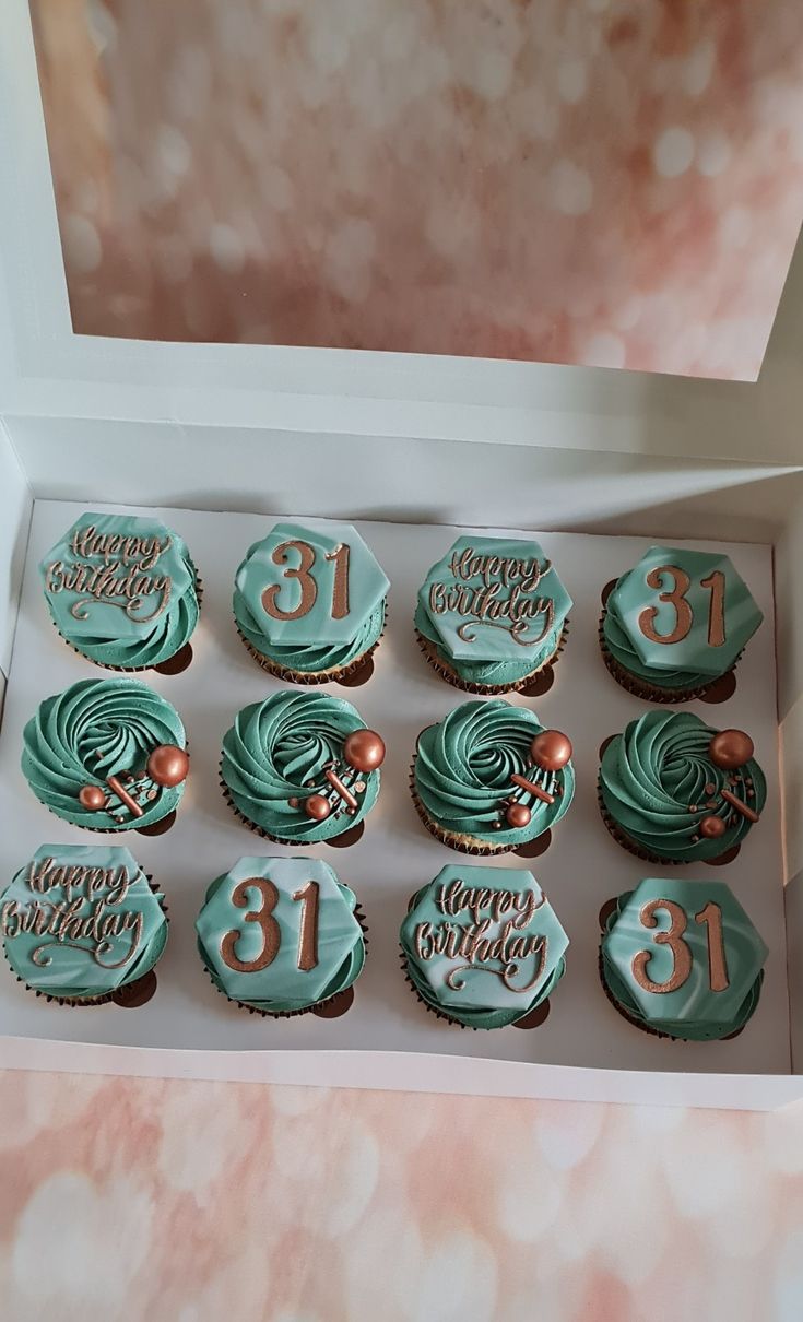 twelve cupcakes in a white box decorated with blue frosting and gold numbers