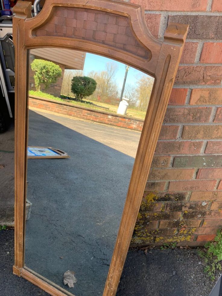 a large wooden mirror sitting next to a brick wall