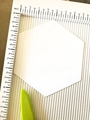 a piece of paper with a ruler next to it and a green object on top