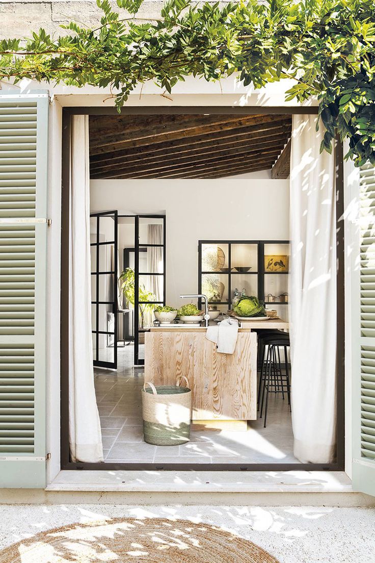 an open door leading to a kitchen and dining area with green plants on the outside