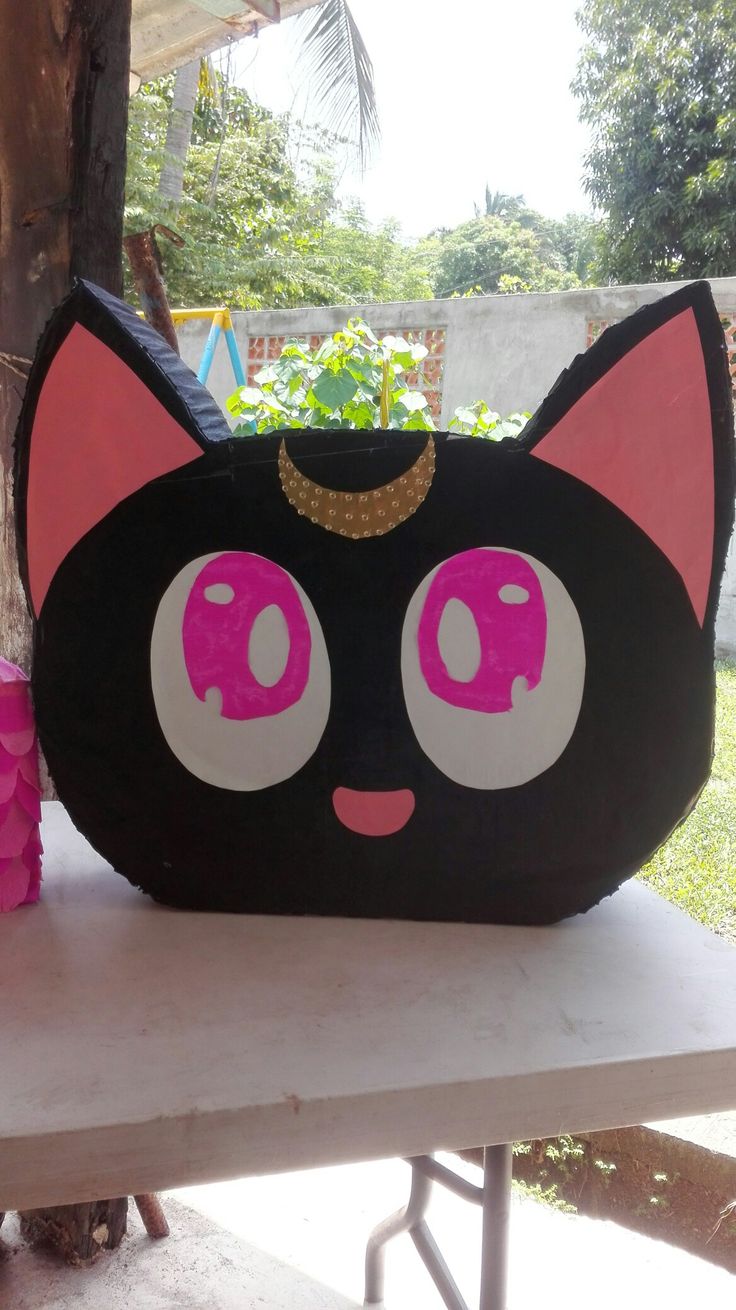 a black and pink cat purse sitting on top of a table next to a tree